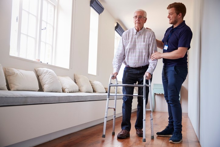A person helping an old person with a walker
